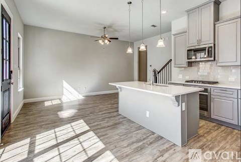 A spacious kitchen with a large island and a ceiling fan.