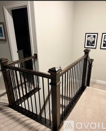 A kitchen with a white island and a staircase with a black railing.