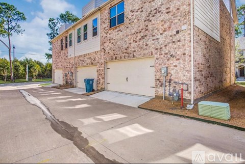 A brick building with a white garage door and a blue trash can.