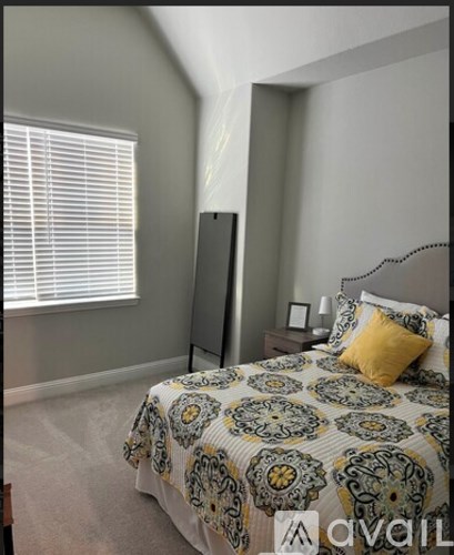 A bedroom with a patterned bedspread and a yellow pillow.