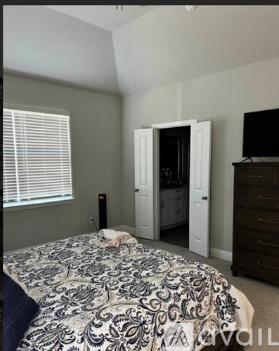 A bedroom with a patterned bedspread and a television in the corner.