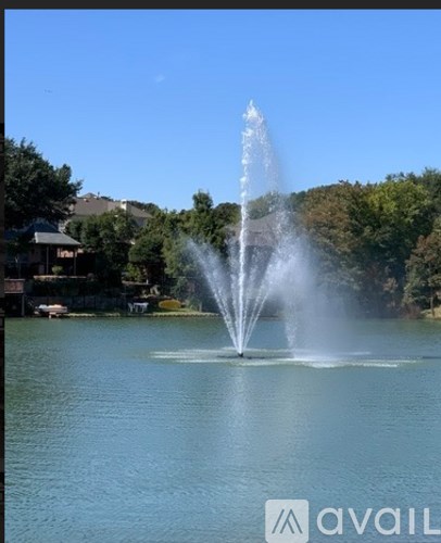 A fountain in the middle of a lake with trees in the background.