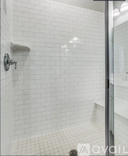 A white tiled shower with a glass door.