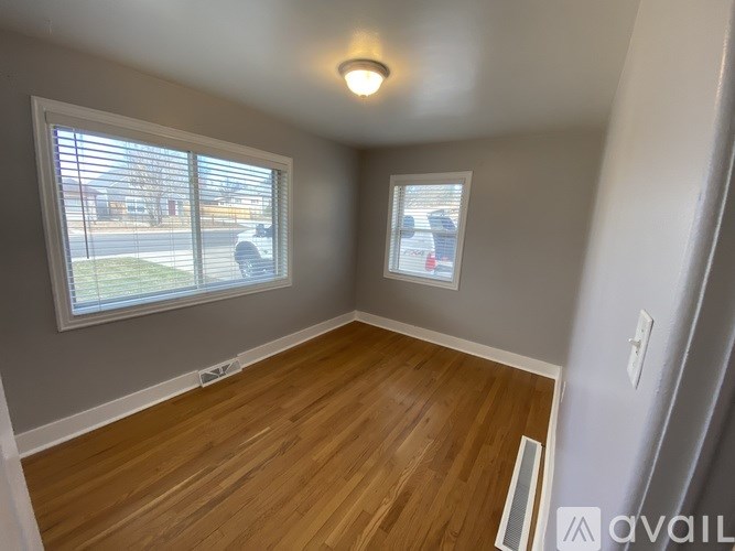 A room with wooden floors and two windows.