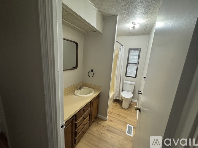 A bathroom with a sink, toilet, and a window.