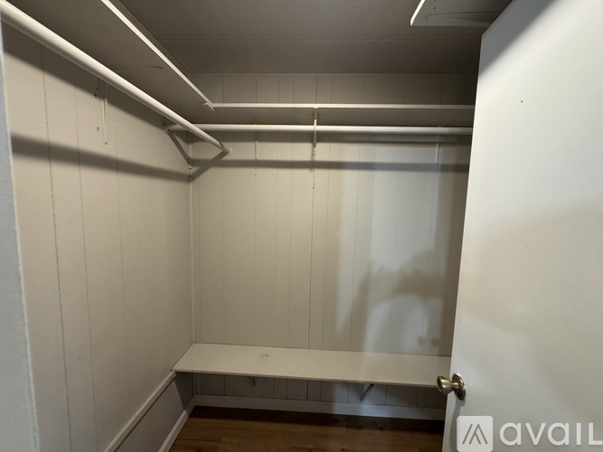 A white room with a bench and a door.