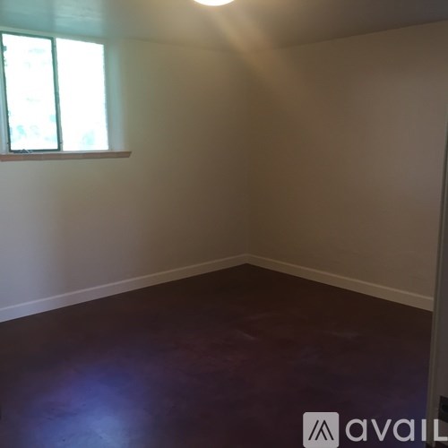 A room with a window and a wooden floor.