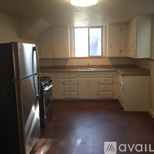 A kitchen with white cabinets and a black refrigerator.
