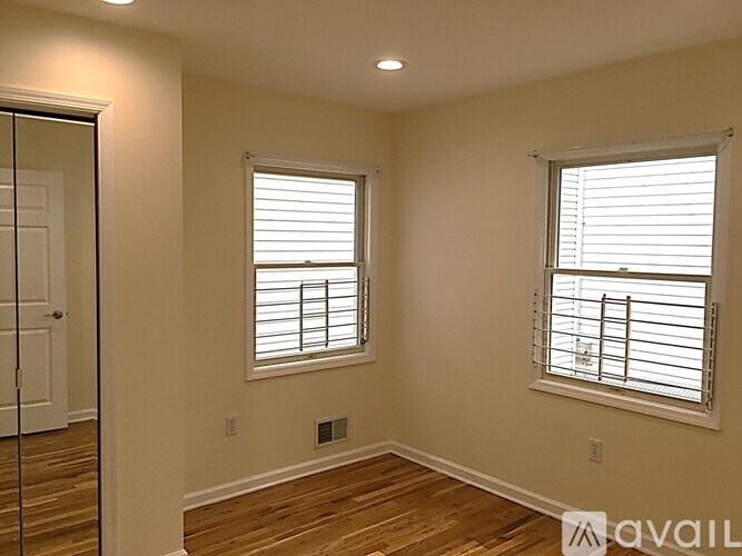 A room with a sliding glass door and two windows with blinds.