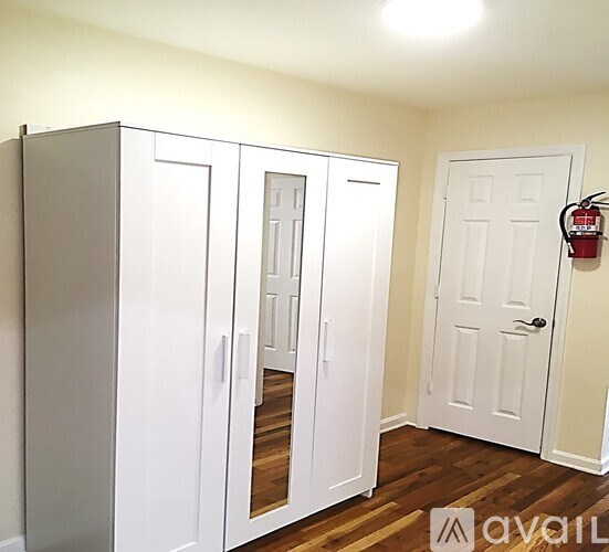 A room with a white door and a white cabinet with a mirror on the door.