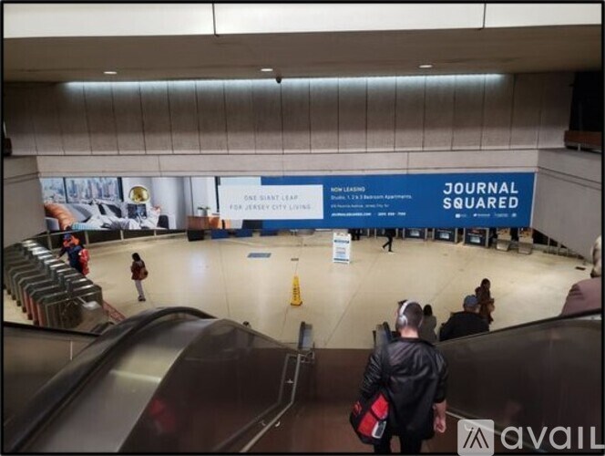 A man in a black jacket carrying a red bag walks through an empty atrium.