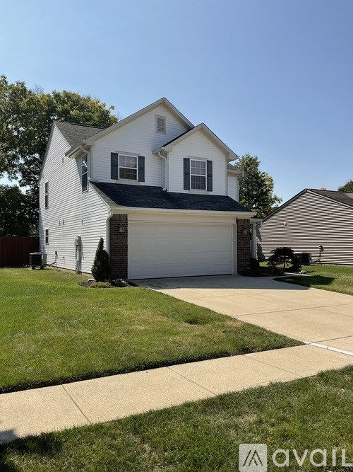 A white house with a black roof and a garage door.