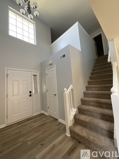 A staircase with a carpeted runner and white balusters leads up to a landing with a window.