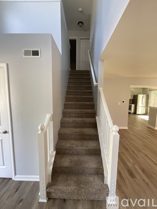 A staircase with a carpet runner and white balusters.
