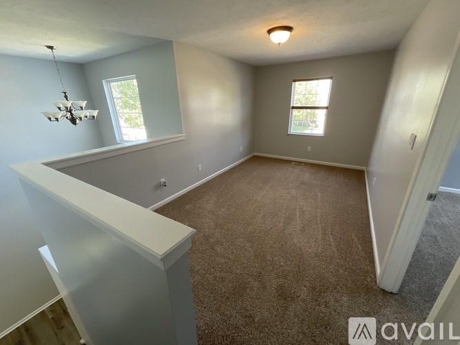 A room with a carpeted floor and two windows.