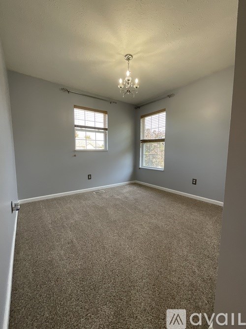 A room with a carpeted floor and a chandelier hanging from the ceiling.