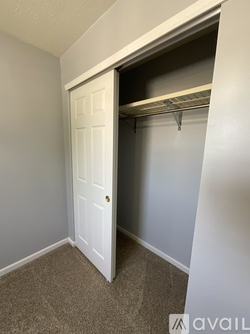 A white door is open to a small closet with a shelf.