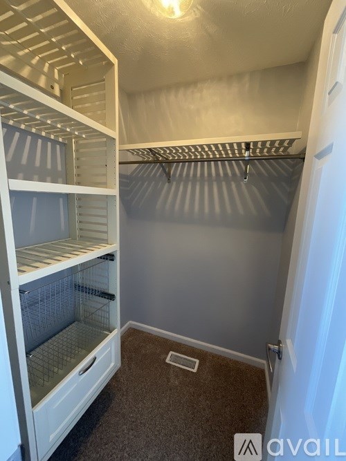 A white refrigerator with a glass door is in a room with a carpeted floor.
