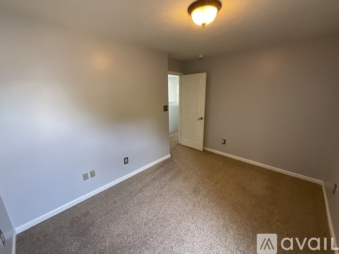 A room with a carpeted floor and a door leading to another room.