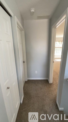 A hallway with a carpeted floor and white walls.