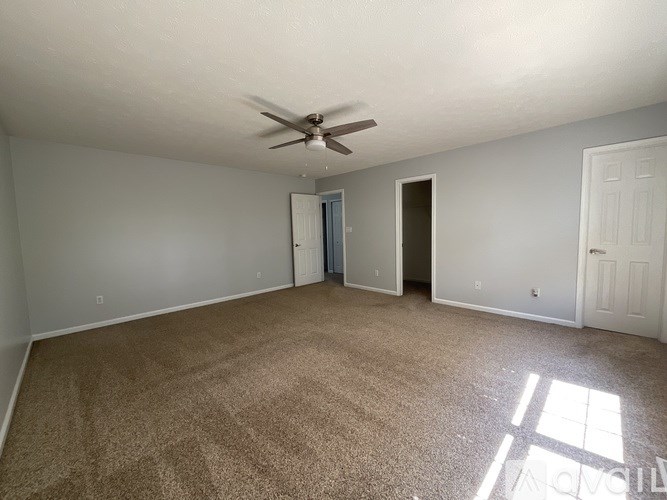A room with a ceiling fan and carpeted floor.