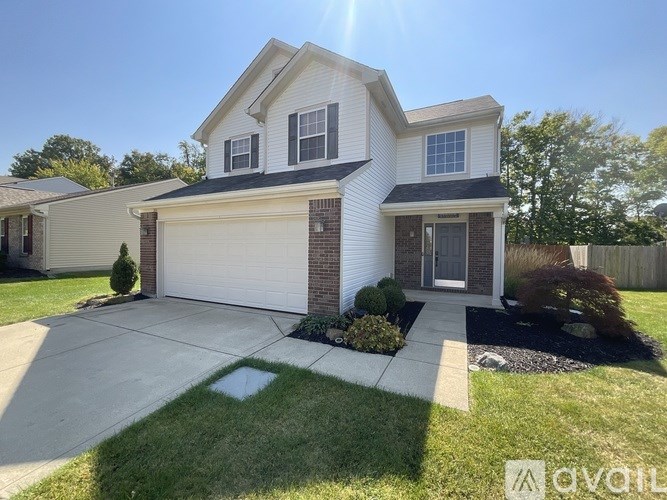 A white house with a grey roof and a garage door.