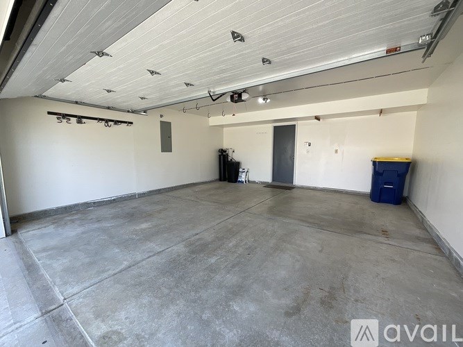 A large, empty garage with a blue bin and a black machine.