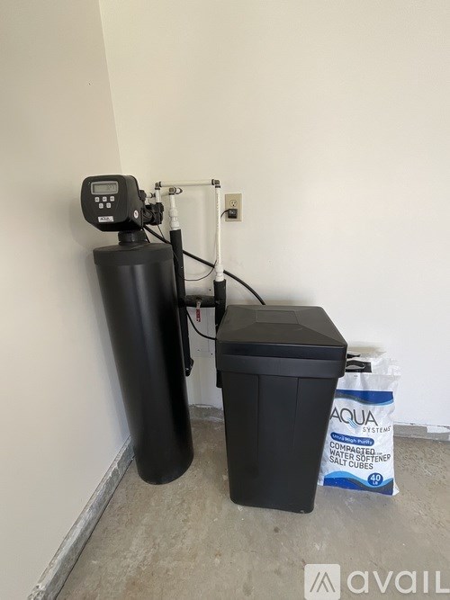 A black water softener system with a digital controller and a bag of Aqua Command water softener pellets.