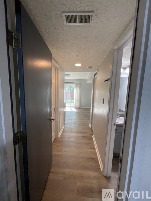 A long hallway with a door on the left and a kitchen area on the right.