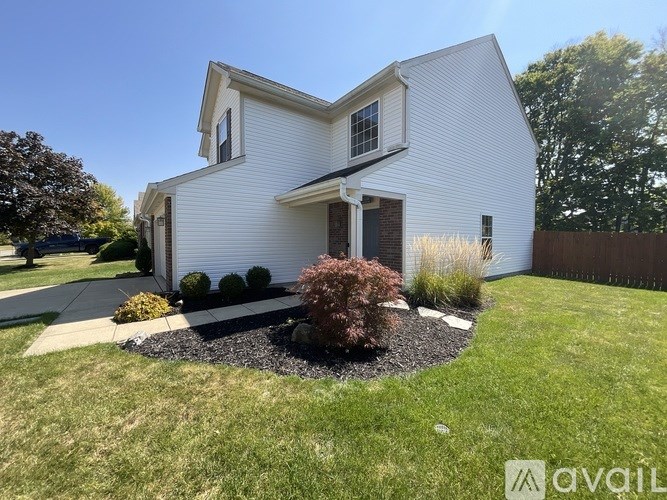A white house with a small front yard and a fence.