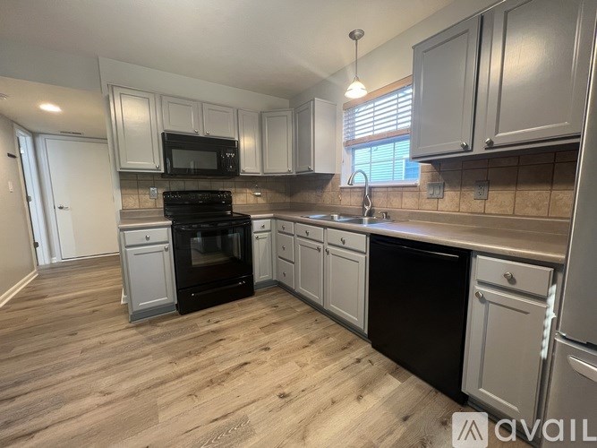 A kitchen with black appliances and white cabinets.