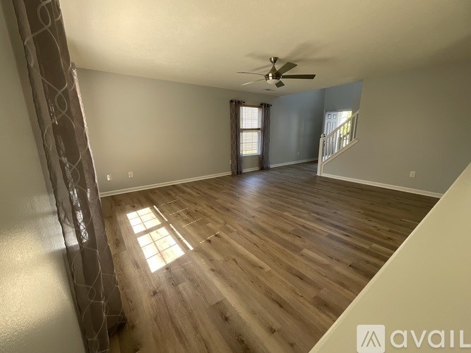 A spacious room with wooden flooring and a ceiling fan.