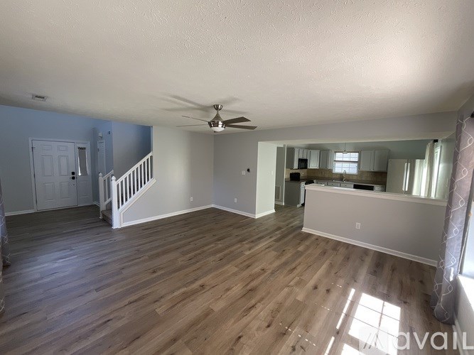 A spacious room with wood flooring and a ceiling fan.