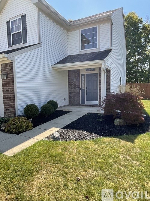 A white house with a black front door and a small garden in front.