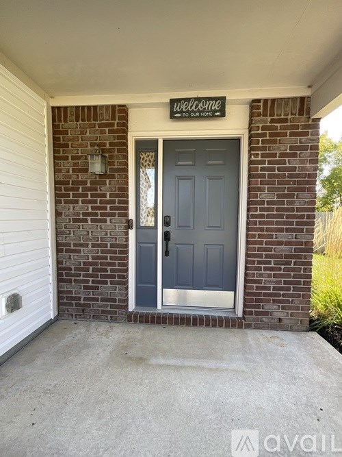 A house entrance with a grey door and a sign that says "welcome".