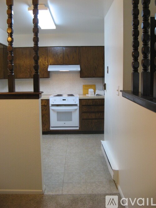 A kitchen with a white stove top oven and wooden cabinets.