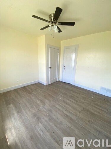 A room with a ceiling fan and two doors.