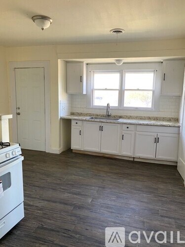 A kitchen with white cabinets and a stove top oven.