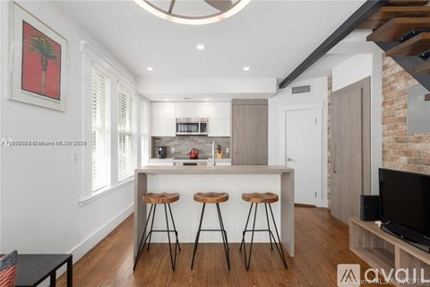 A kitchen with a bar stool and a framed picture of a palm tree.