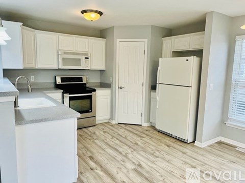 A kitchen with white cabinets and a white refrigerator.