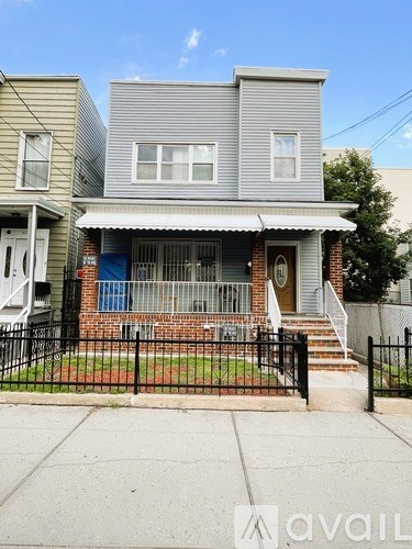 A two-story house with a front porch and a black fence.