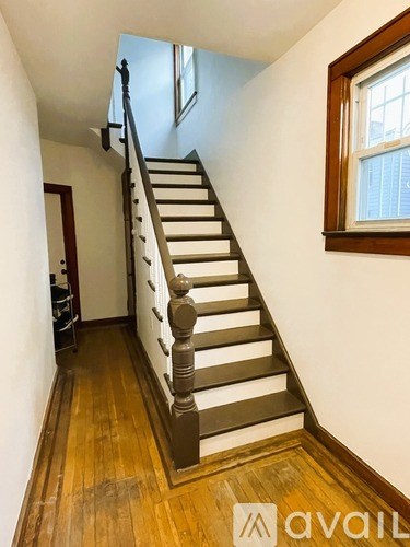 A wooden staircase with a black handrail.