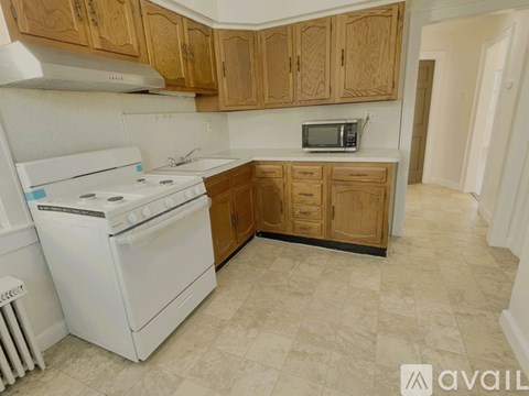 A kitchen with a white stove and wooden cabinets.