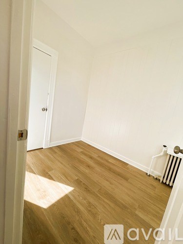 A room with wooden floors and a white wall with a door.