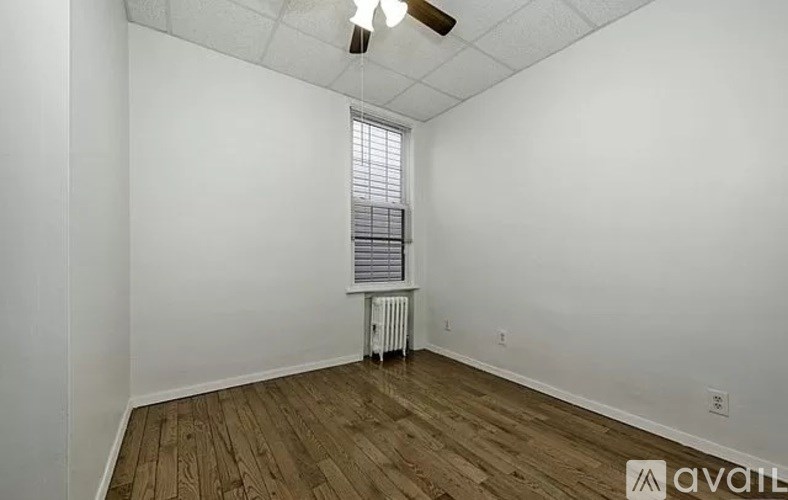 A room with wooden floors and a window with blinds.
