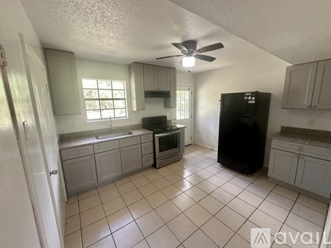 A kitchen with a black refrigerator and white ceiling fan.