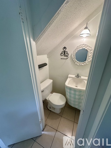 A bathroom with a toilet, sink, and mirror.