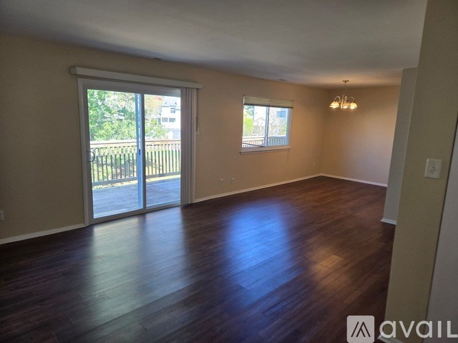 A room with wooden floors and a sliding glass door leading to a balcony.
