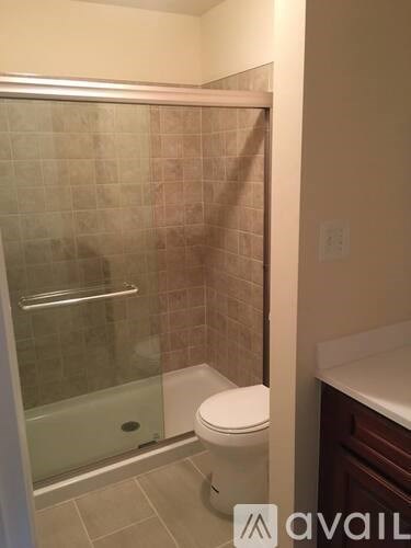 A bathroom with a toilet, a glass shower stall, and a sink.