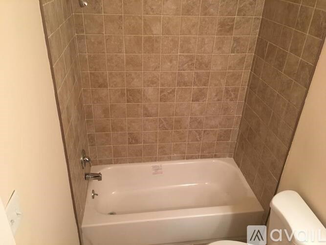 A white bathtub in a bathroom with beige tiled walls.